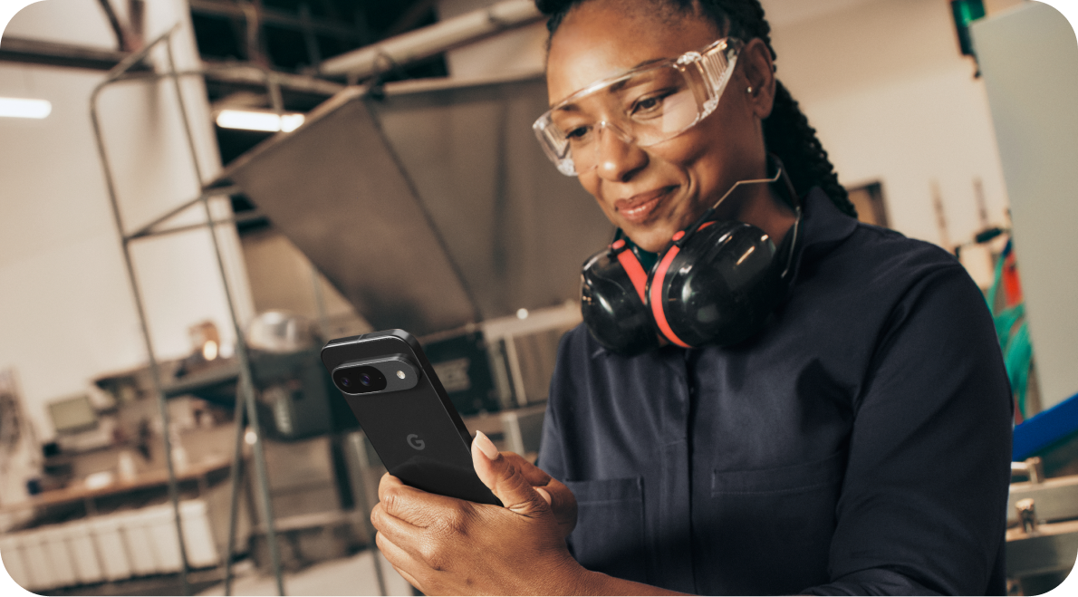 A woman working on her Google Pixel 9 phone in a warehouse.