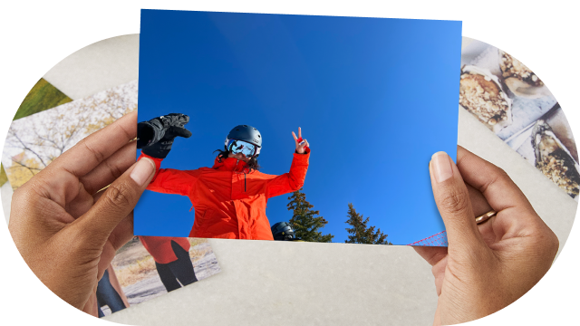 A photo print of a skier holding up a peace sign under a blue sky.