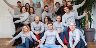 The Teester team is sitting for a group photo with matching grey sweaters.